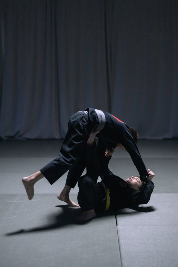Services Two men engaged in intense Brazilian Jiu Jitsu sparring match indoors.