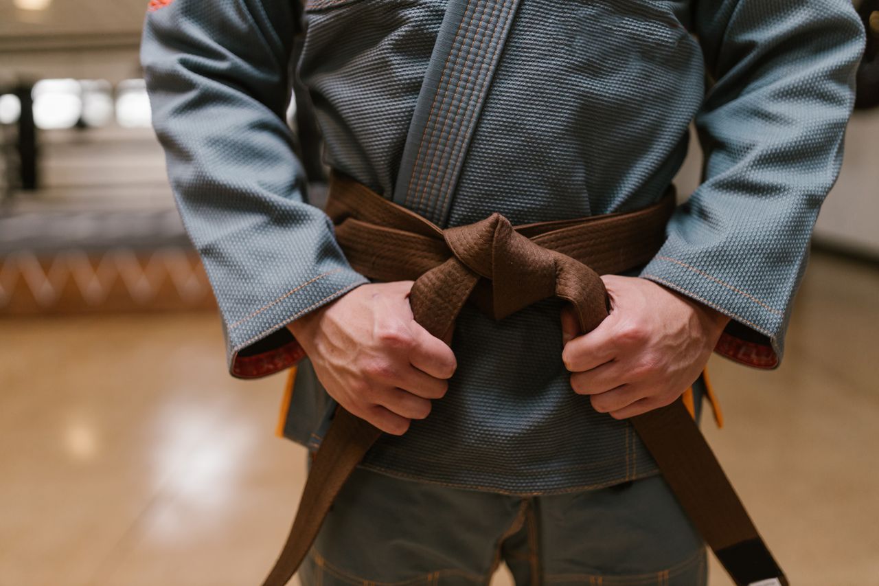 About Close-up of a martial artist tying a brown belt, highlighting discipline and skill in combat sports.